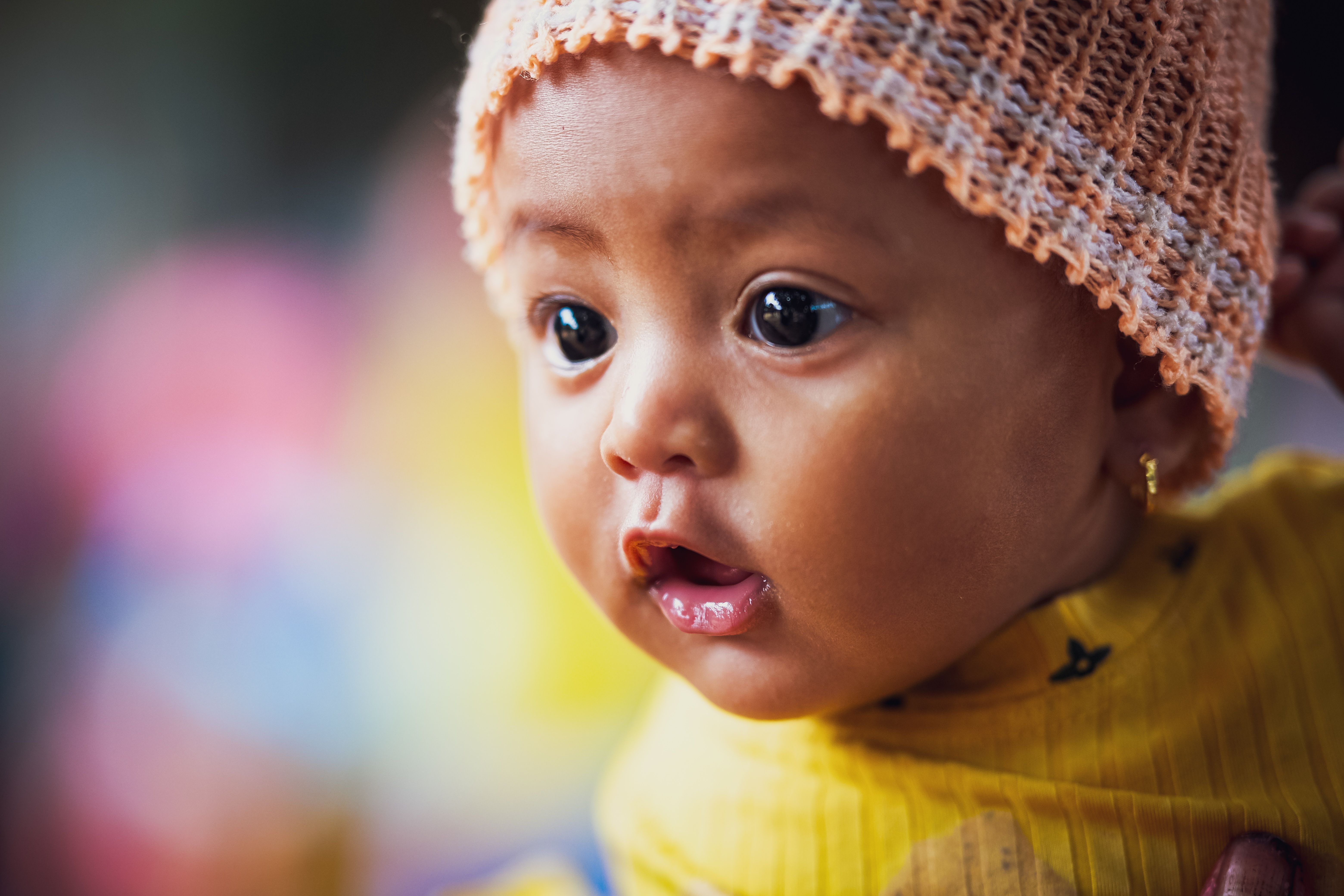 Charming portrait of a baby wearing a knitted cap, showcasing an innocent and curious expression.