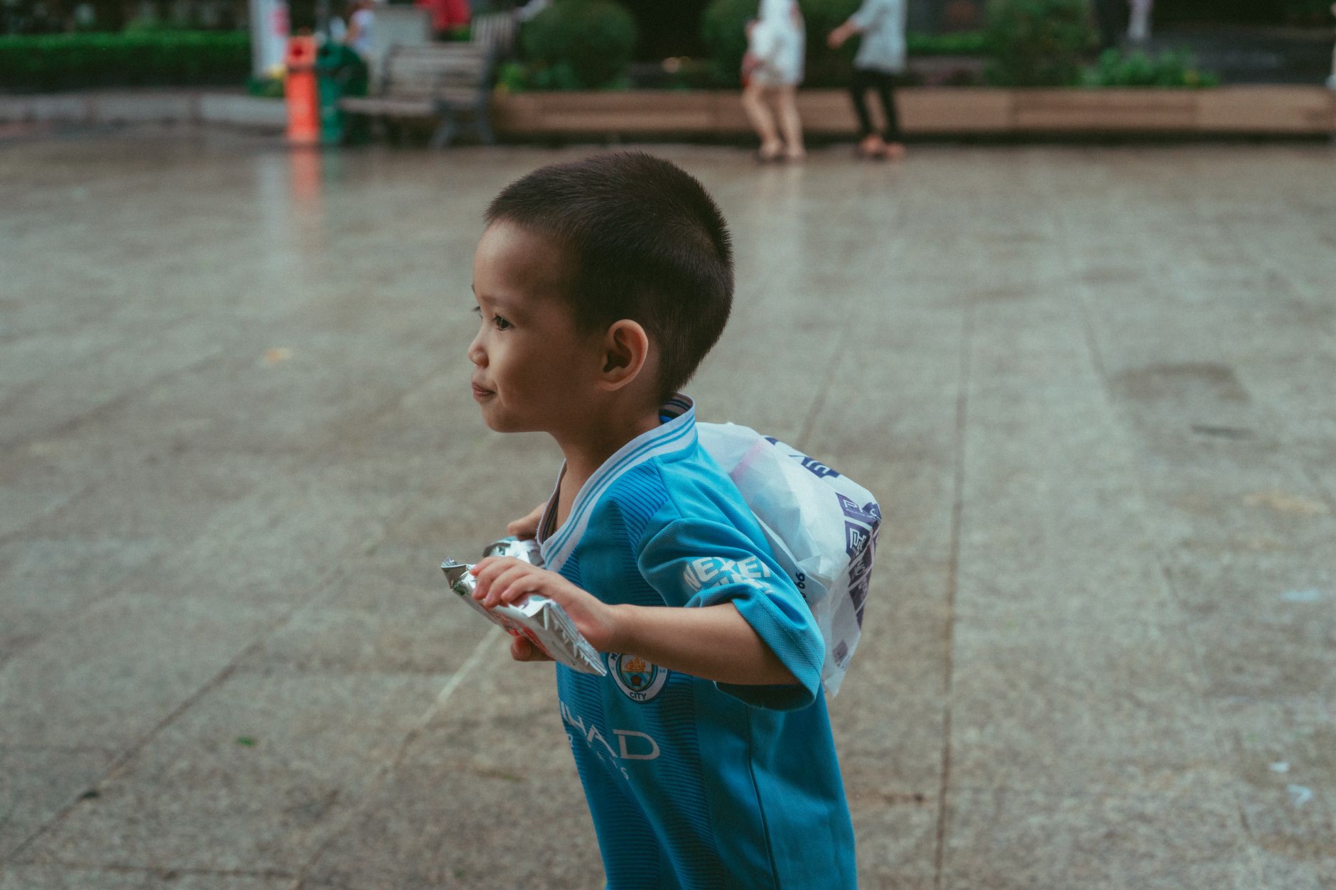 A young child runs joyfully in a vibrant street scene in Ho Chi Minh City, Vietnam.