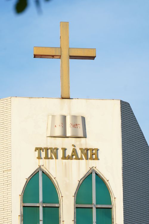 Free Facade of a Christian church with a cross and 'Tin Lành' text under a blue sky. Stock Photo
