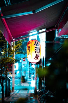 Traditional Japanese lantern illuminating a city street at night with vibrant neon colors.