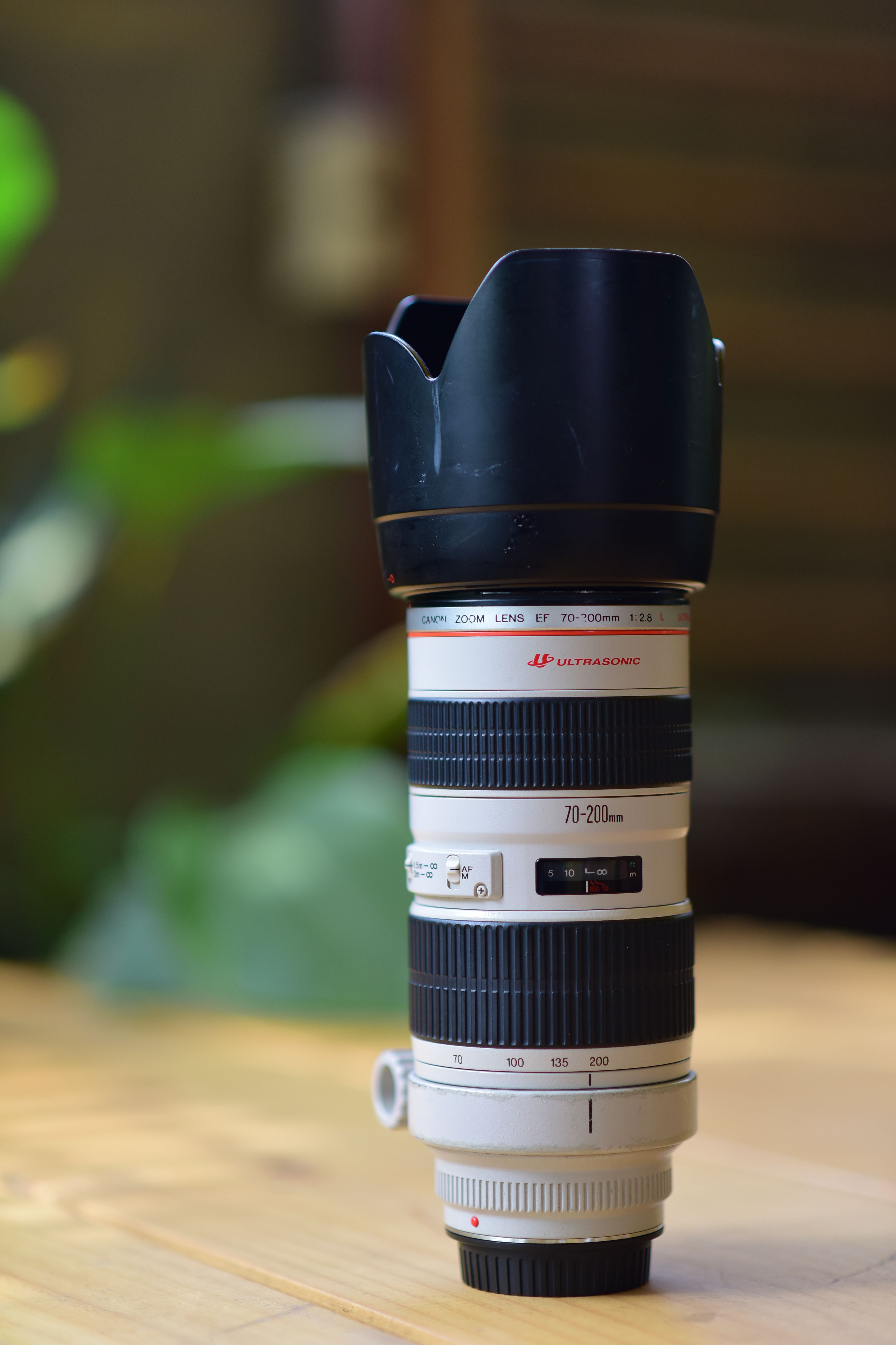 Close-up of a professional camera lens with hood on a wooden table, ideal for photography enthusiasts.