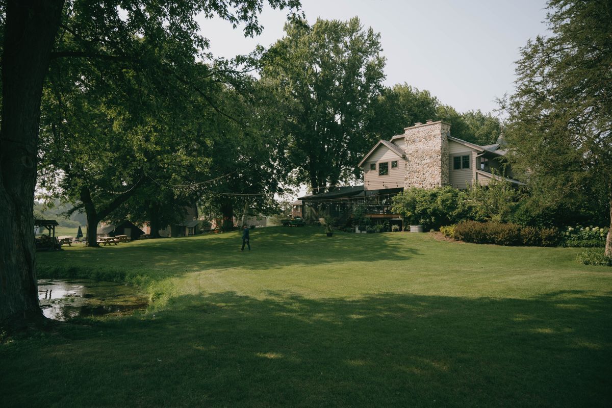 Two-story house with a green lawn and mature trees, shown as a residential scene