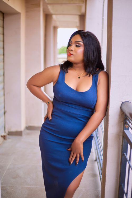 Free Stylish woman in a blue dress standing confidently by a corridor railing. Stock Photo