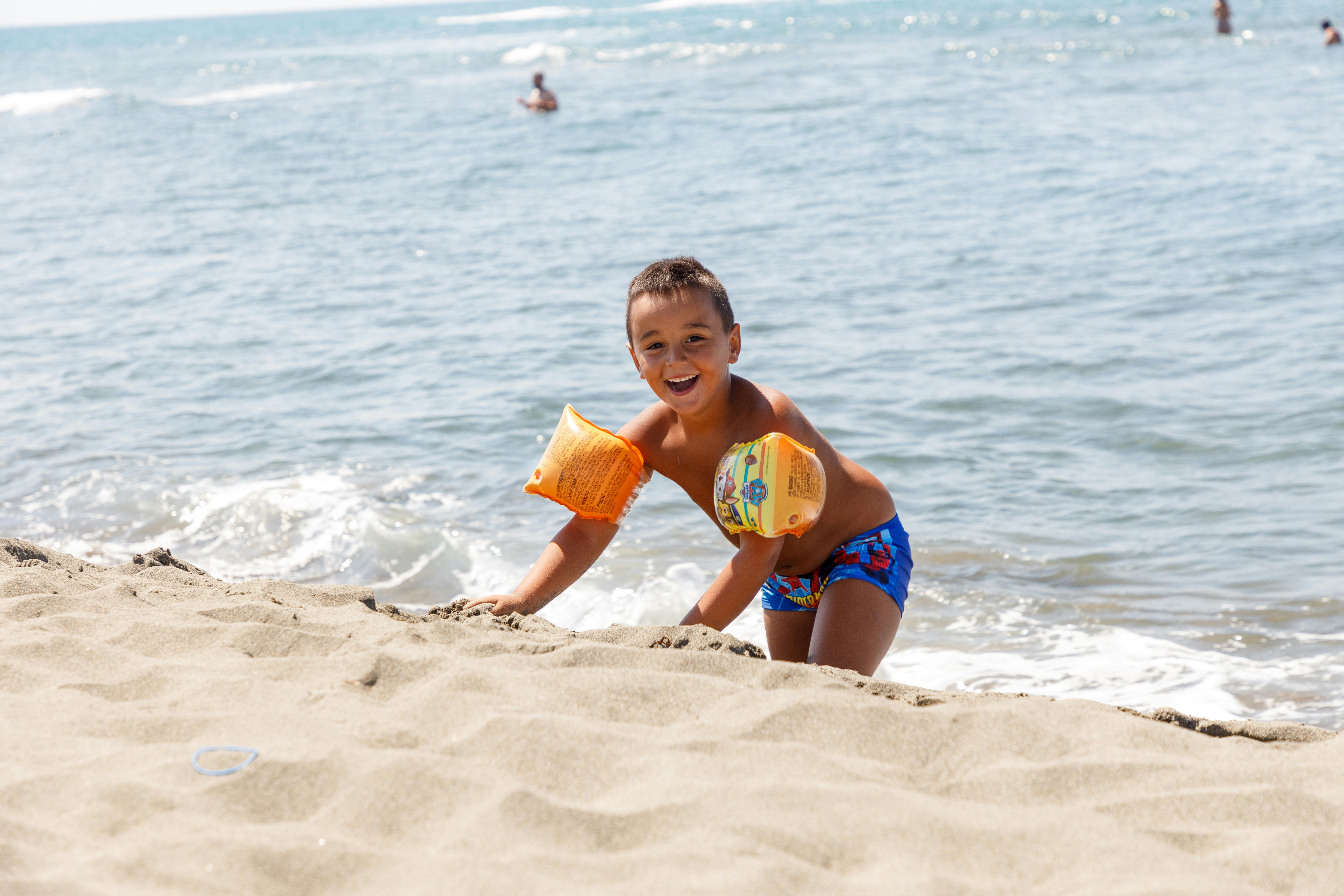 Smiling child with floaties enjoying a sunny day at Ulcinj beach, Montenegro.