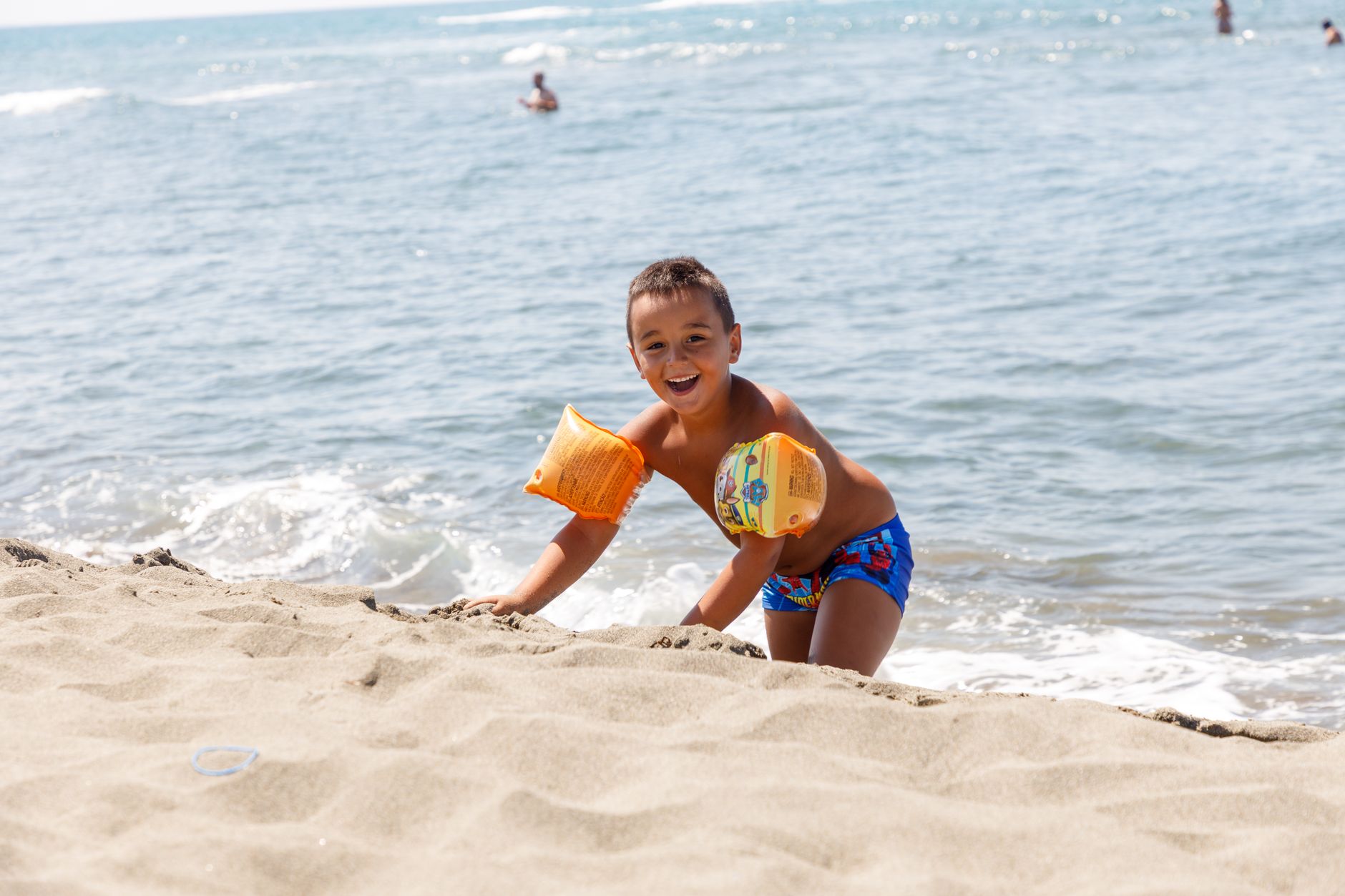 Smiling child with floaties enjoying a sunny day at Ulcinj beach, Montenegro.