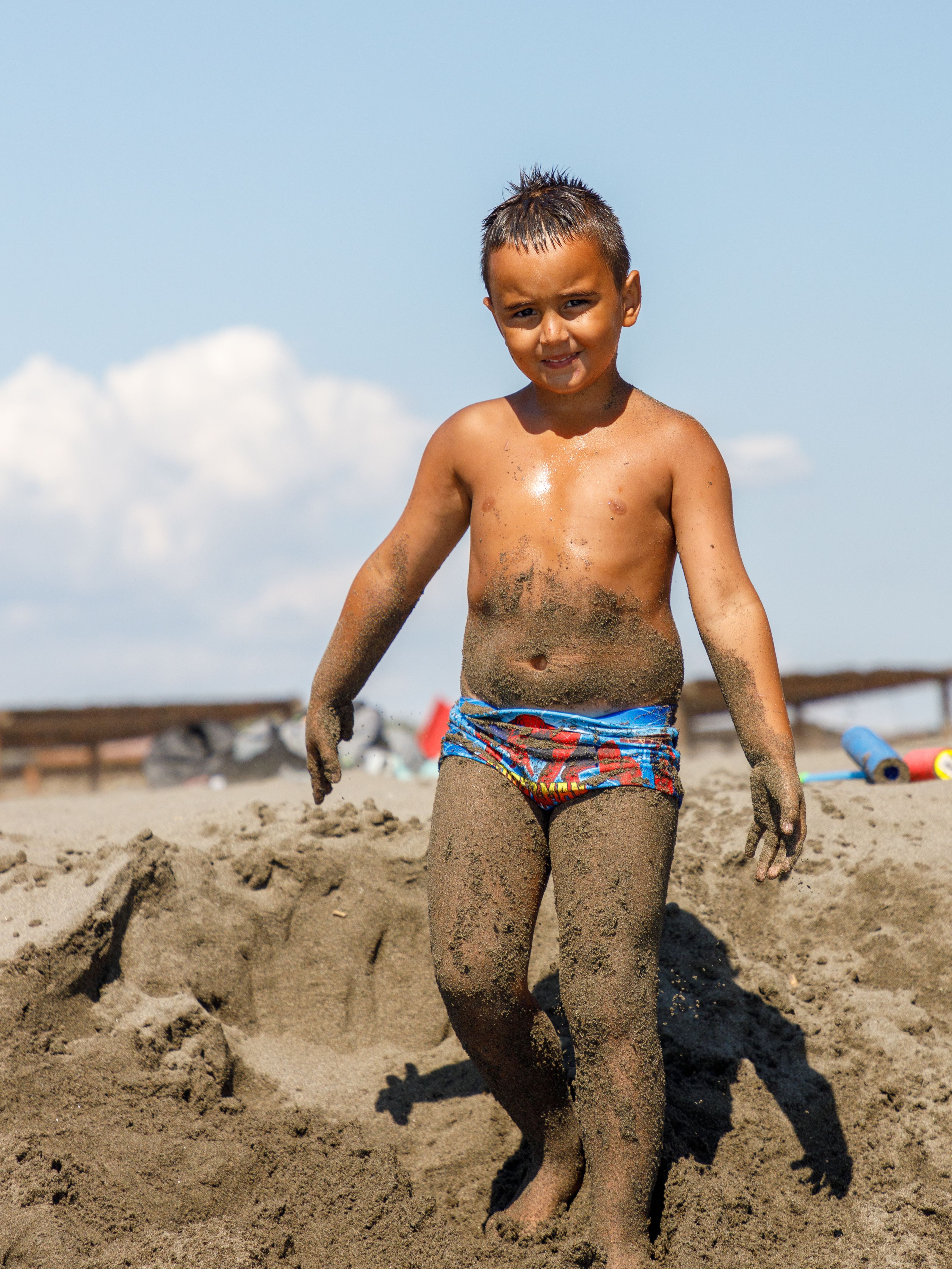Um menino coberto de areia aproveitando um dia ensolarado na praia em Ulcinj, Montenegro.