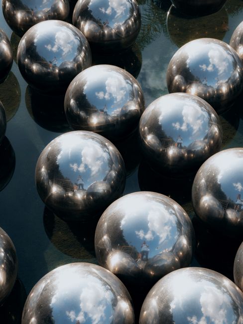 Artistic metal spheres reflecting sky and surroundings in an outdoor setting in MG, Brazil.