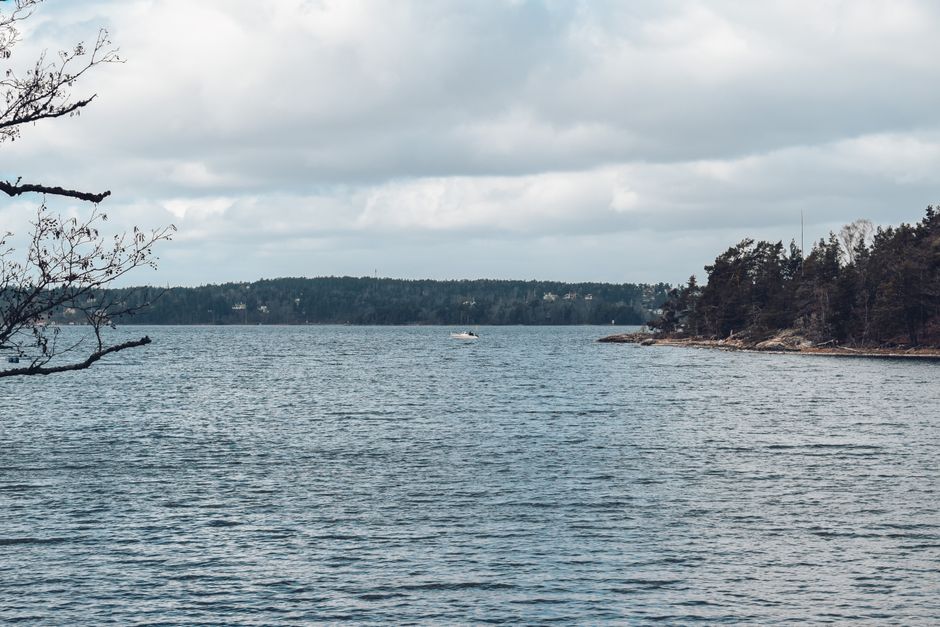Calm waters and forested shores of Stockholm archipelago under a cloudy sky.