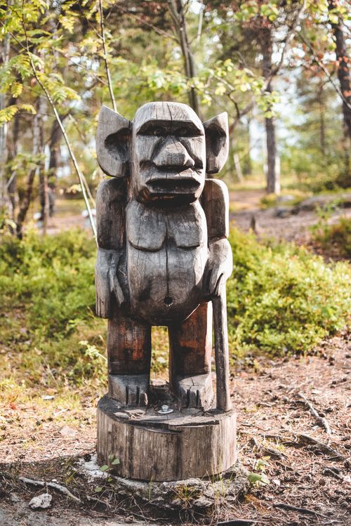 Free A rustic woodcarving of a mythical troll stands in a serene Swedish woodland setting. Stock Photo