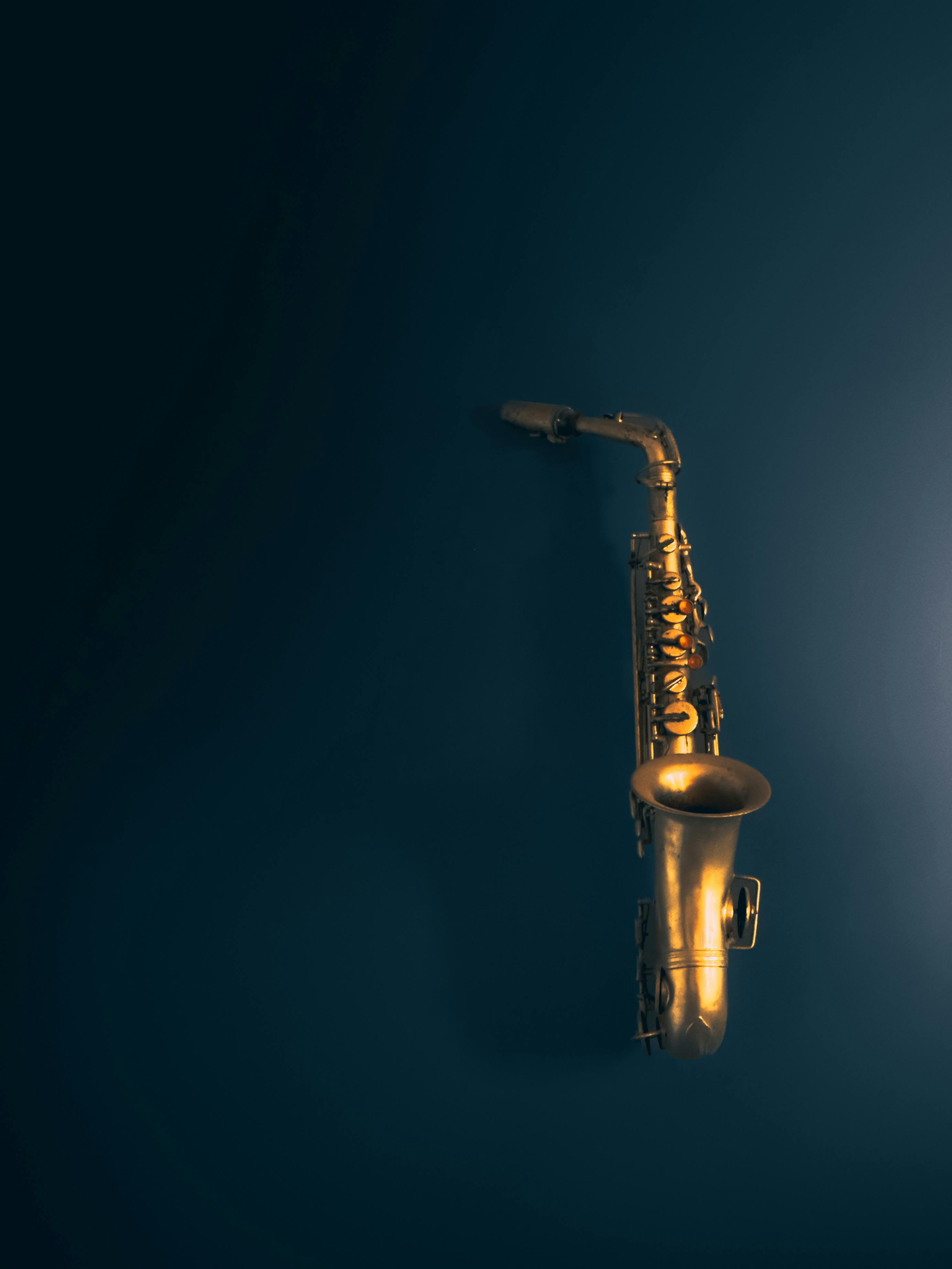 Zadarmo Dychový saxofón na tmavom pozadí vyžarujúci eleganciu a hudobné čaro. Fotka z fotobanky