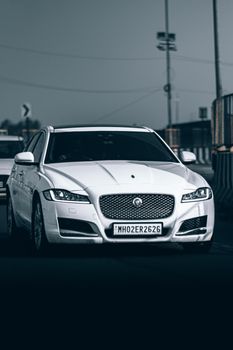 White luxury car driving on a city road, showcasing elegance and speed in an urban setting.