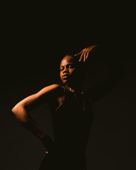 Captivating portrait of a stylish dancer posing creatively in warm lighting.