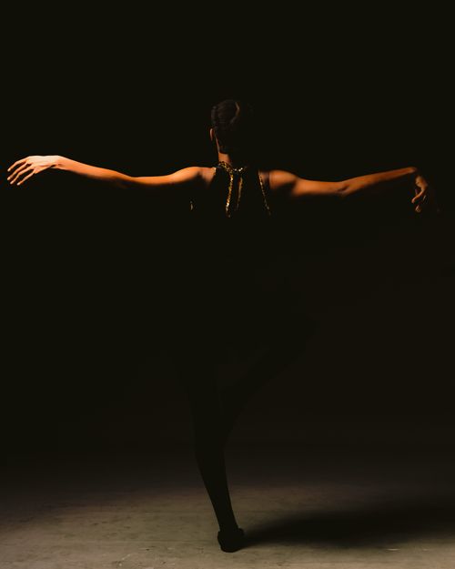 Free Artistic silhouette of a dancer poised gracefully, capturing elegance and movement in dim lighting. Stock Photo