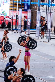 Female athletes lifting weights in a CrossFit competition, showcasing strength and determination.