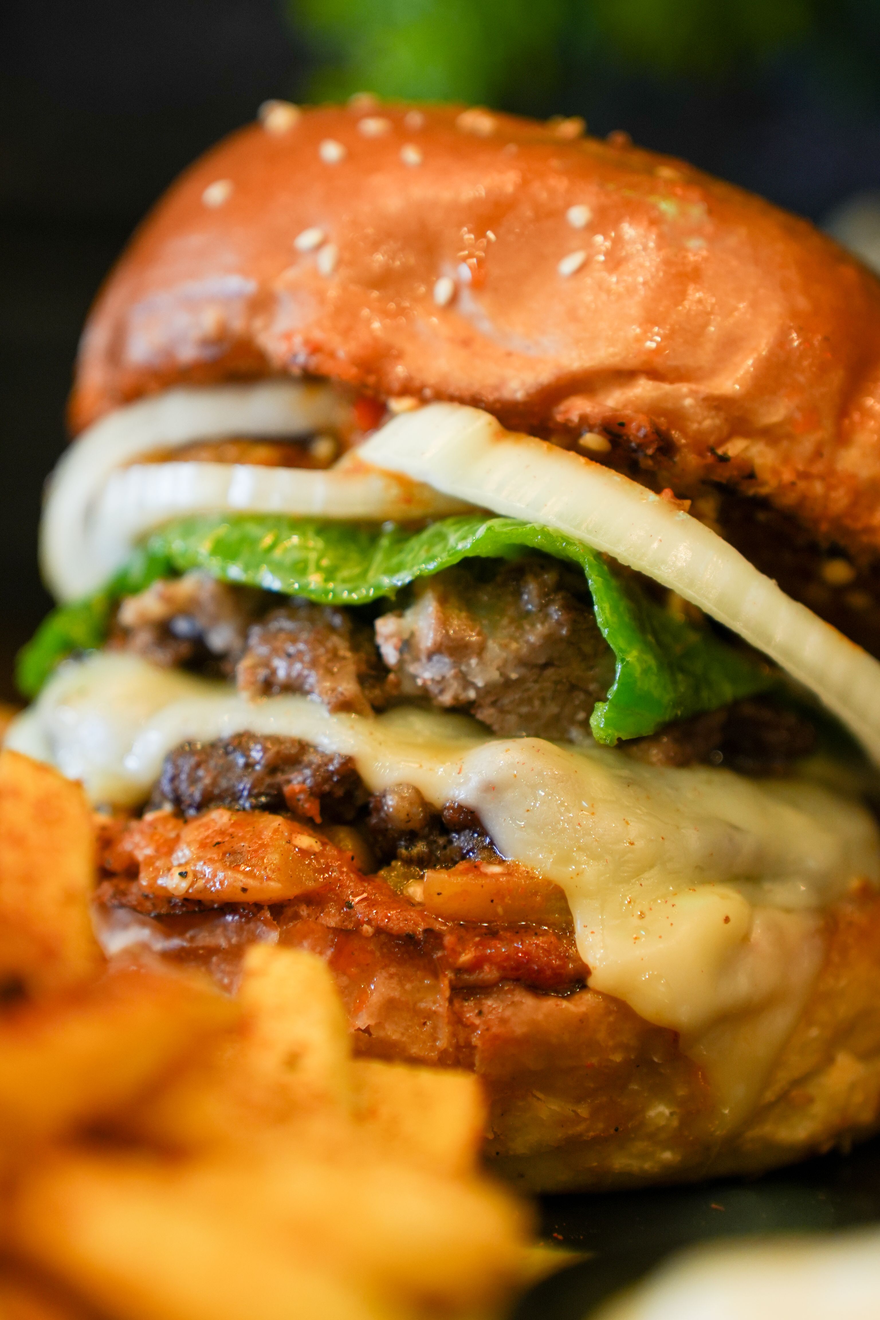 Delicious cheeseburger with layers of onion, lettuce, cheese, served with crispy fries.