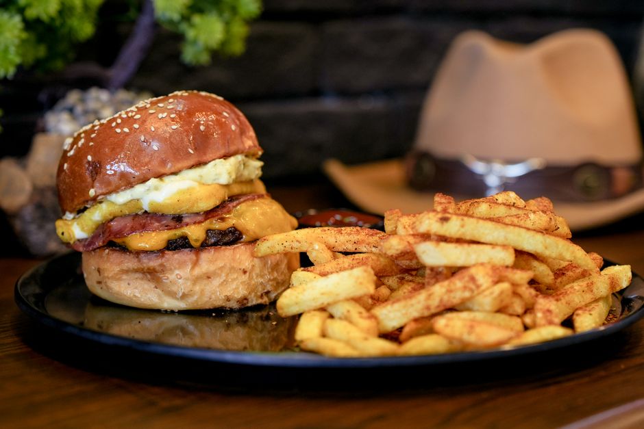 Mouth-watering cheeseburger with fries served on a rustic wooden table.