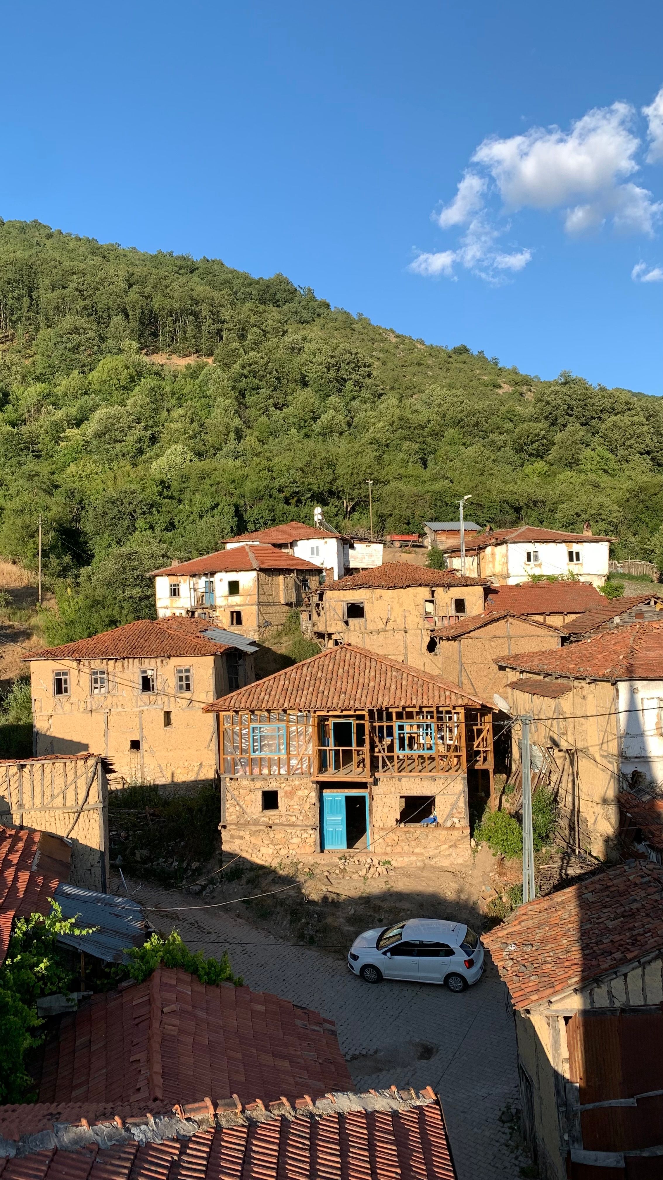 Traditional village with rustic houses nestled in lush green mountains under a clear blue sky.