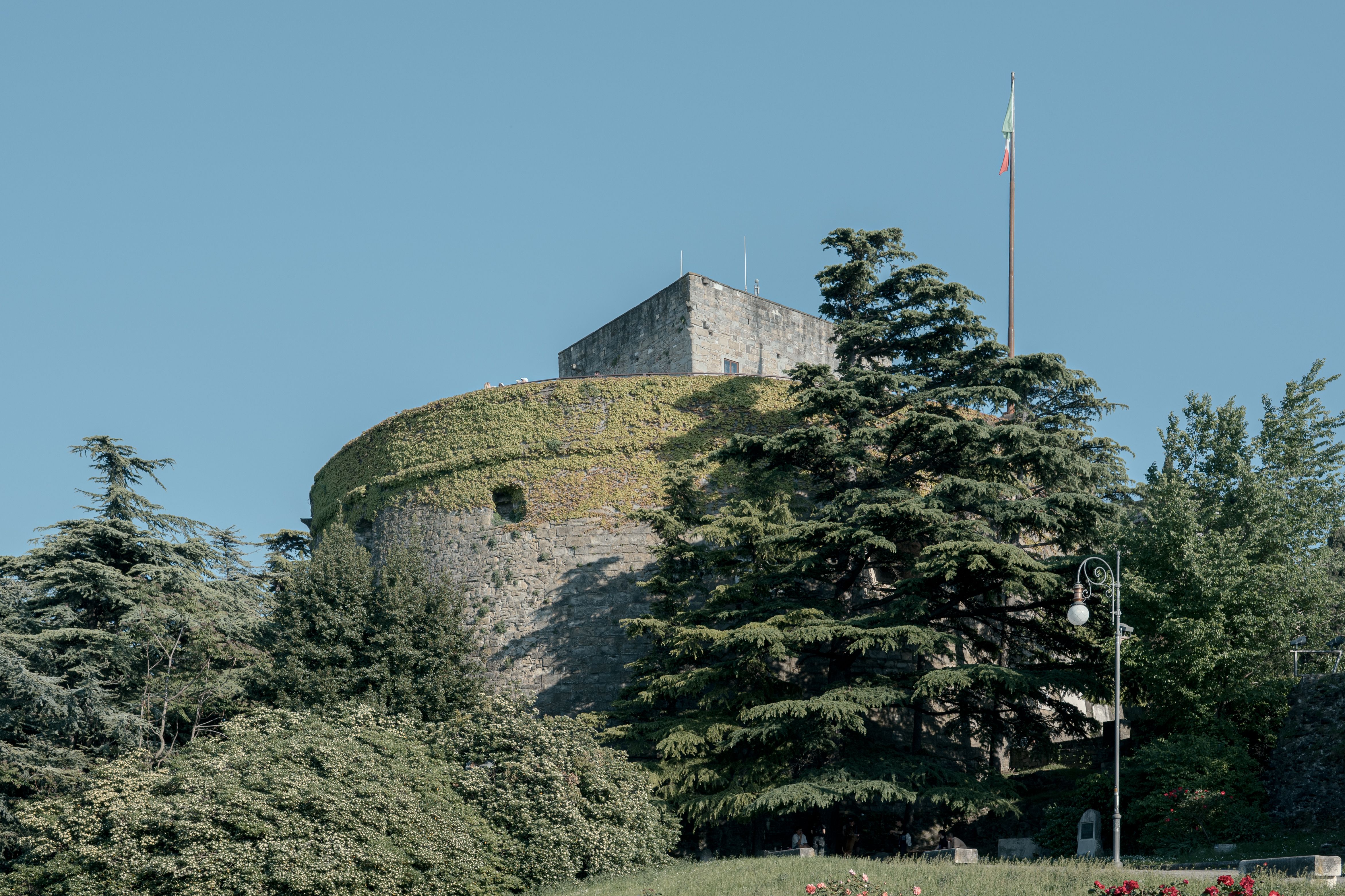San Giusto Castle with lush greenery and a clear blue sky in Trieste, Italy.