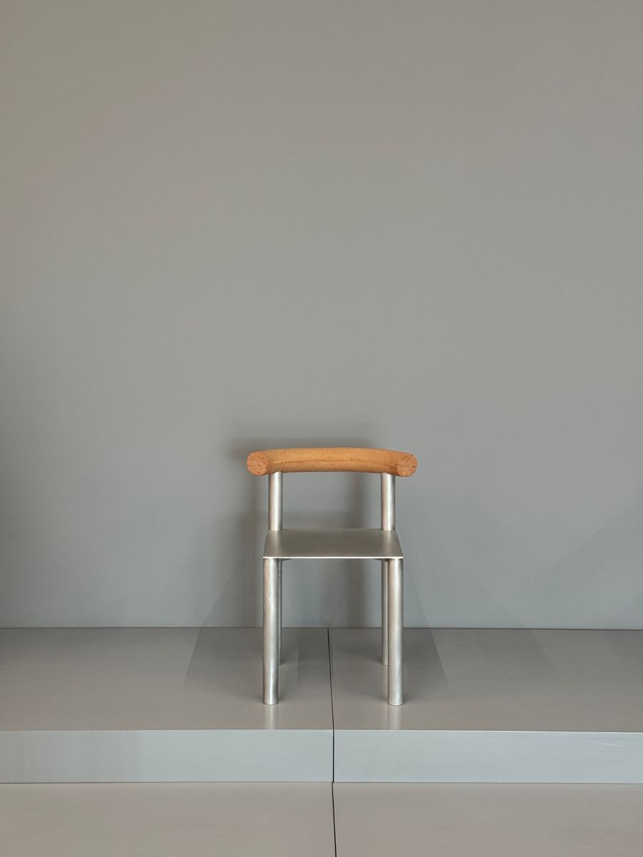 A minimal chair in aluminium and timber against a plain wall - photo by lumverte on Pexels