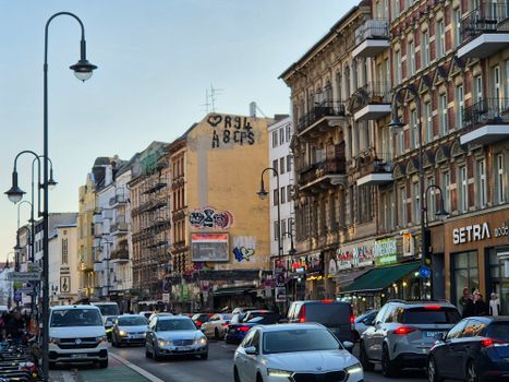 A lively urban street scene with classic architecture, cars, and pedestrians.