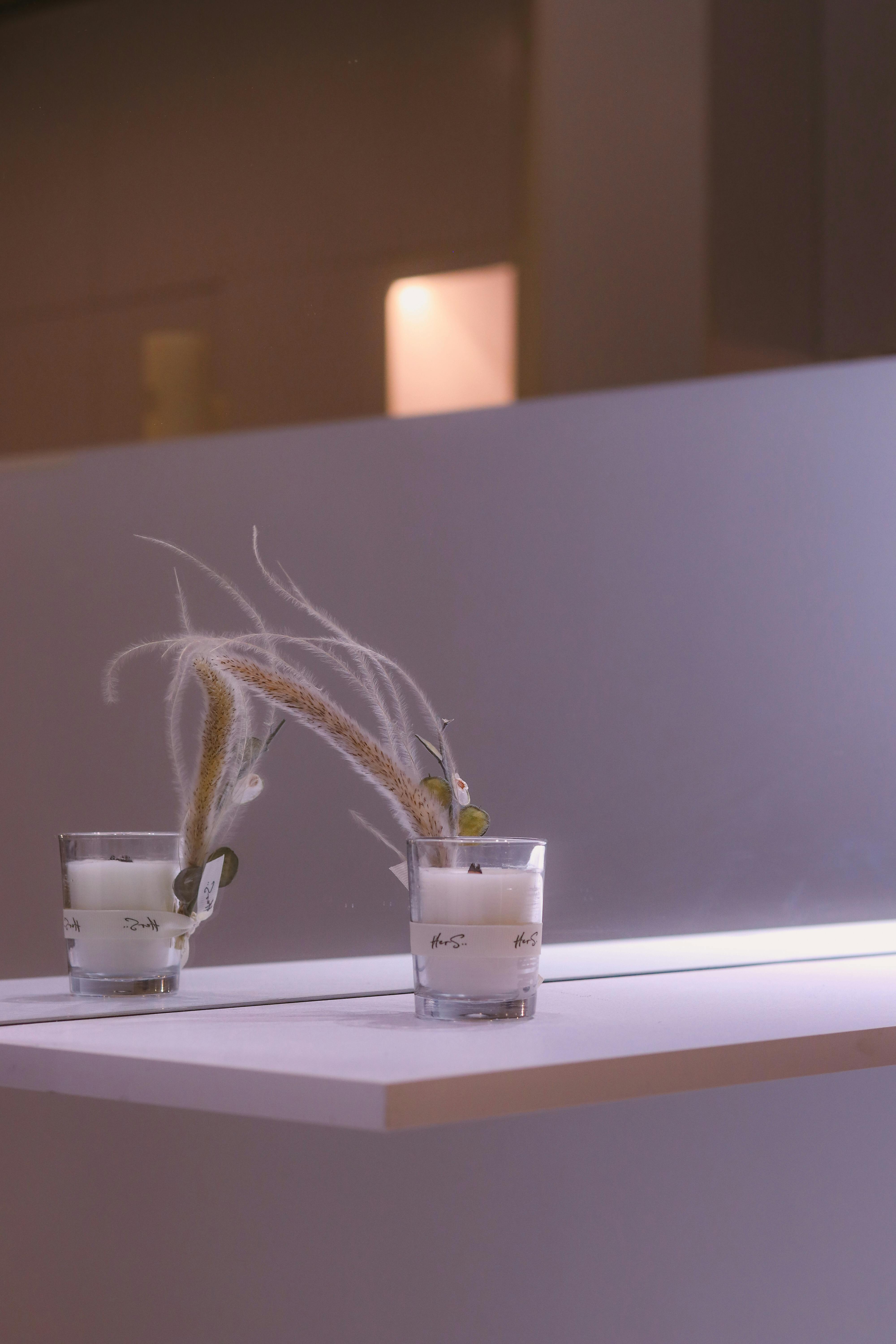 gratis Minimalistisch ontwerp met glazen kaarsen op een witte plank met zachte verlichting. Stockfoto