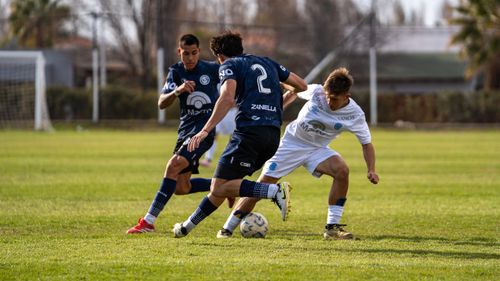 Free Intense soccer game between two teams in blue and white jerseys on a grassy outdoor field. Stock Photo