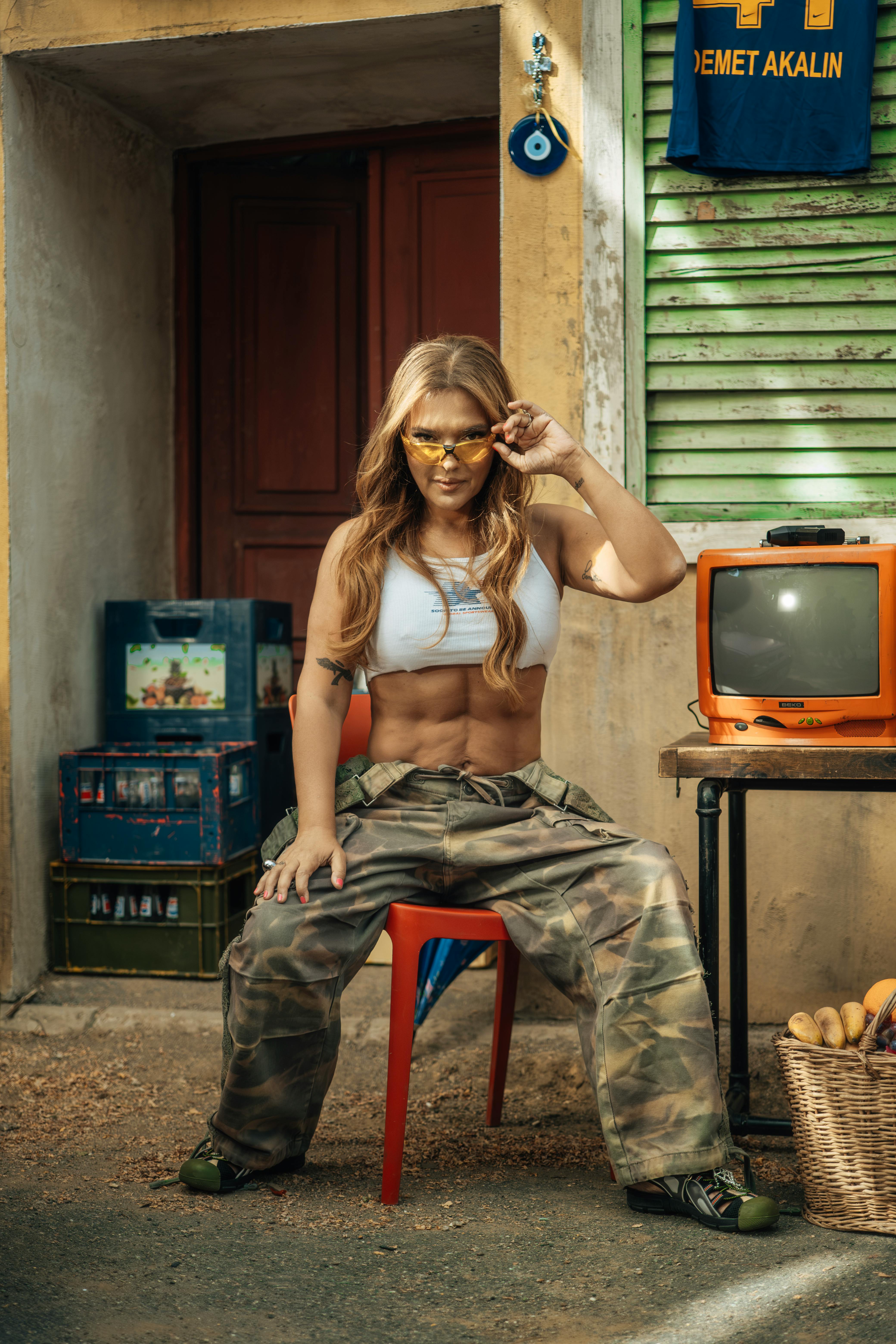 Stylish woman in streetwear posing with retro items in urban setting.
