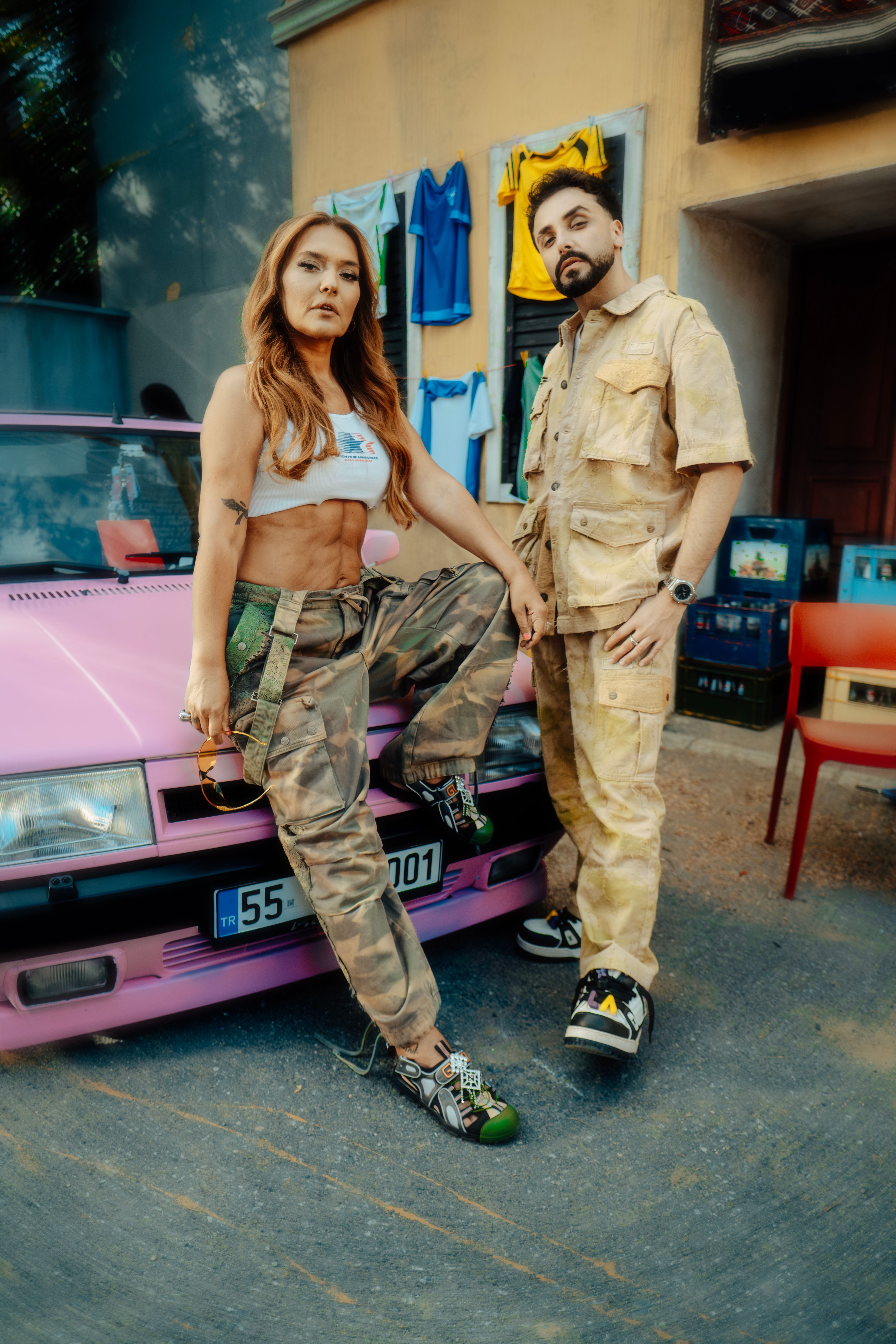 Stylish portrait of two adults in trendy clothes next to a pink vintage car.