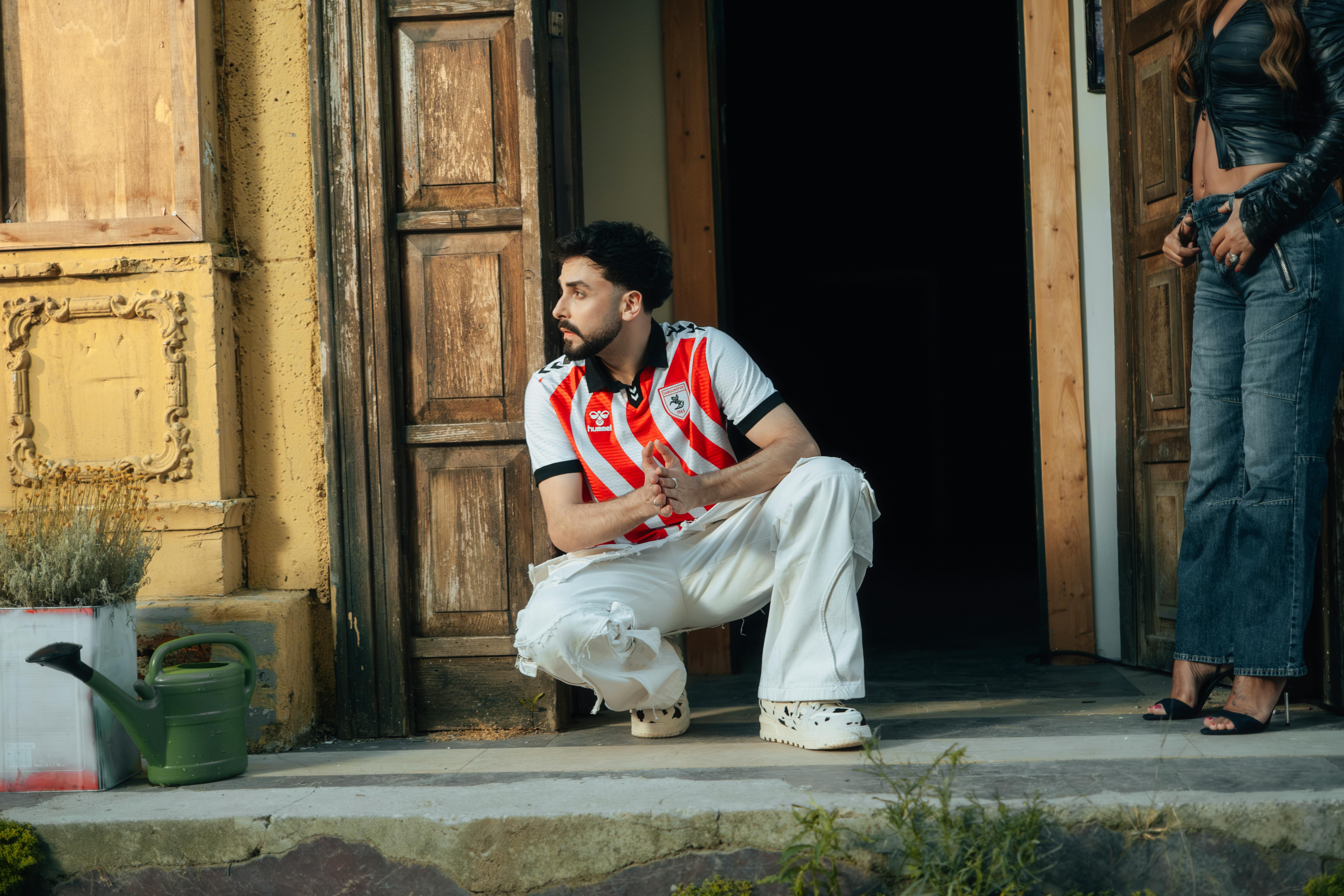 Man and woman in modern outfits on a rustic porch with vintage doors.