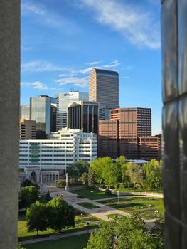 View of Denver's modern skyline with distinctive skyscrapers and lush greenery below.