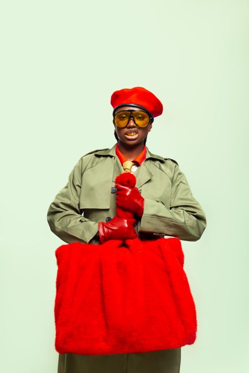 Free Fashionable woman in green trench coat and red accessories holding a red bag. Stock Photo