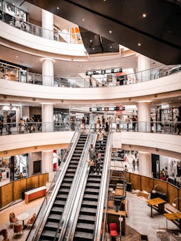 Modern shopping mall interior with vibrant atmosphere, featuring escalators and multiple levels of stores.