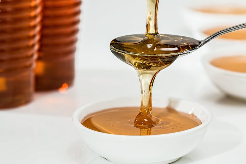 honey pouring on a spoon and in a bowl
