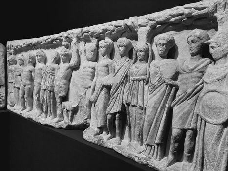 Black and white photo of an ancient stone relief showcasing human figures in İzmir, Türkiye museum.