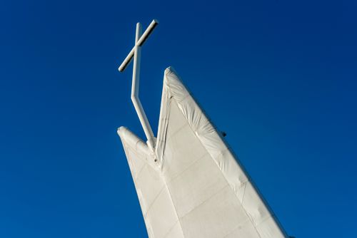 Free Unique modern church design with a striking tower against a clear blue sky. Stock Photo