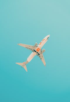 A commercial airplane flies above São Paulo with a clear blue sky, showcasing modern aviation.
