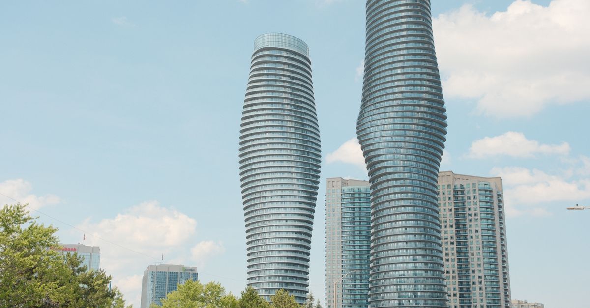 The iconic Absolute Towers of Mississauga, also known as the Marilyn Monroe Towers, against a bright blue sky.