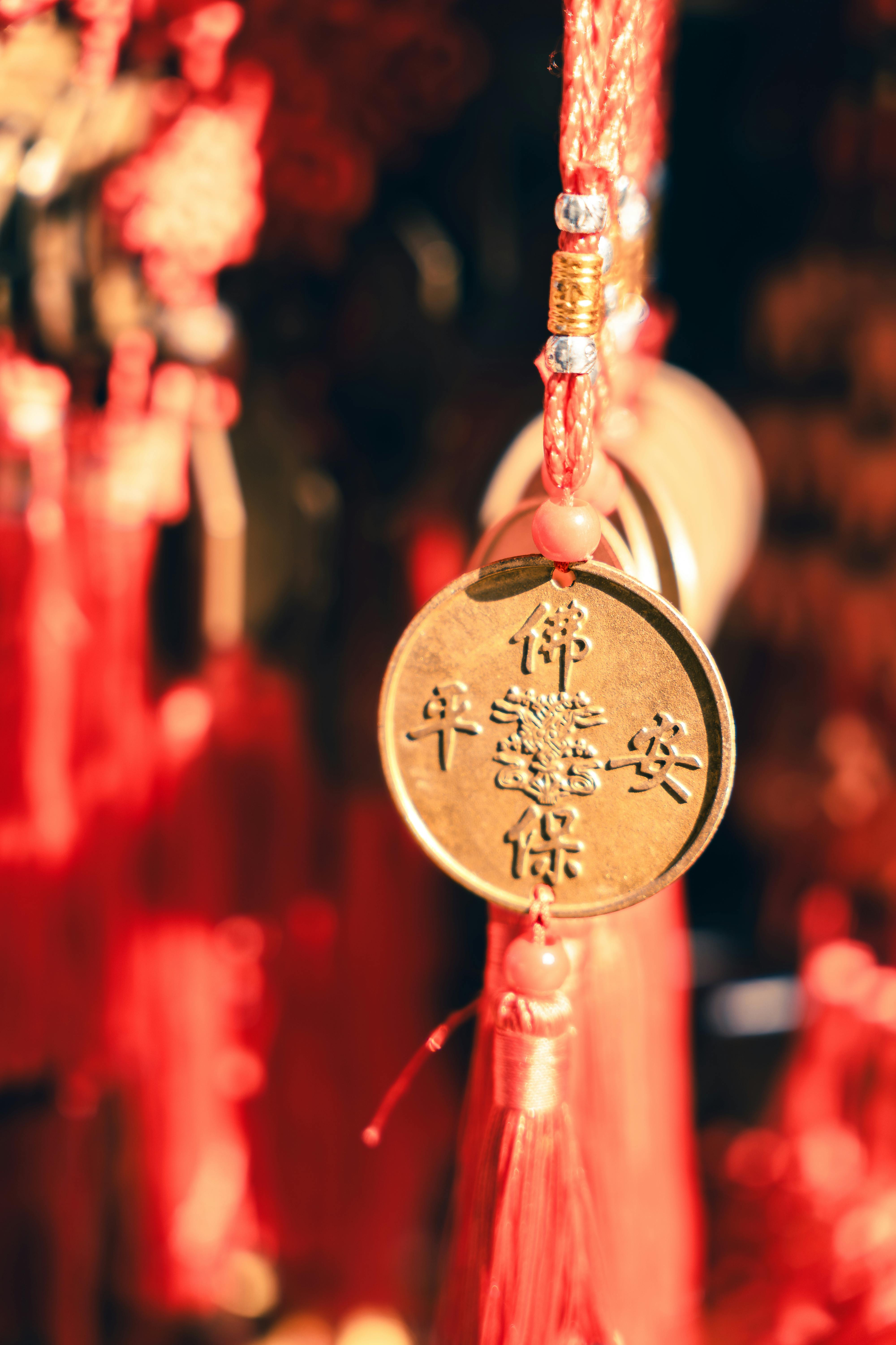 Close-up of red Chinese New Year decoration with golden coin and tassels, symbolizing luck and prosperity.