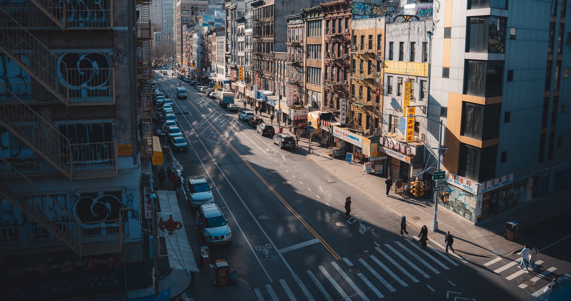 Street view of Chinatown in New York City with pedestrians and historic buildings.
