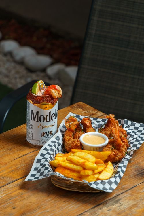 Free Fried chicken with fries and Modelo beer on a wooden table outdoors. Perfect casual dining vibe. Stock Photo