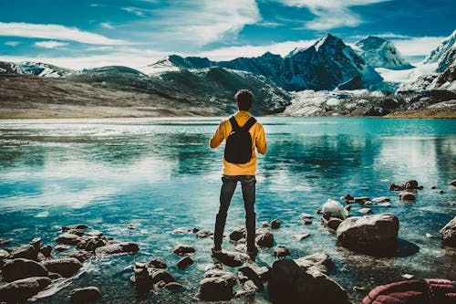 Photo of Man Wearing Backpack While Standing on Rocks