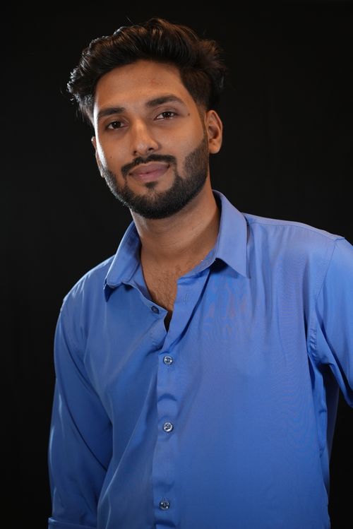 Free Studio portrait of a young man in a blue shirt, looking thoughtful against a dark background. Stock Photo