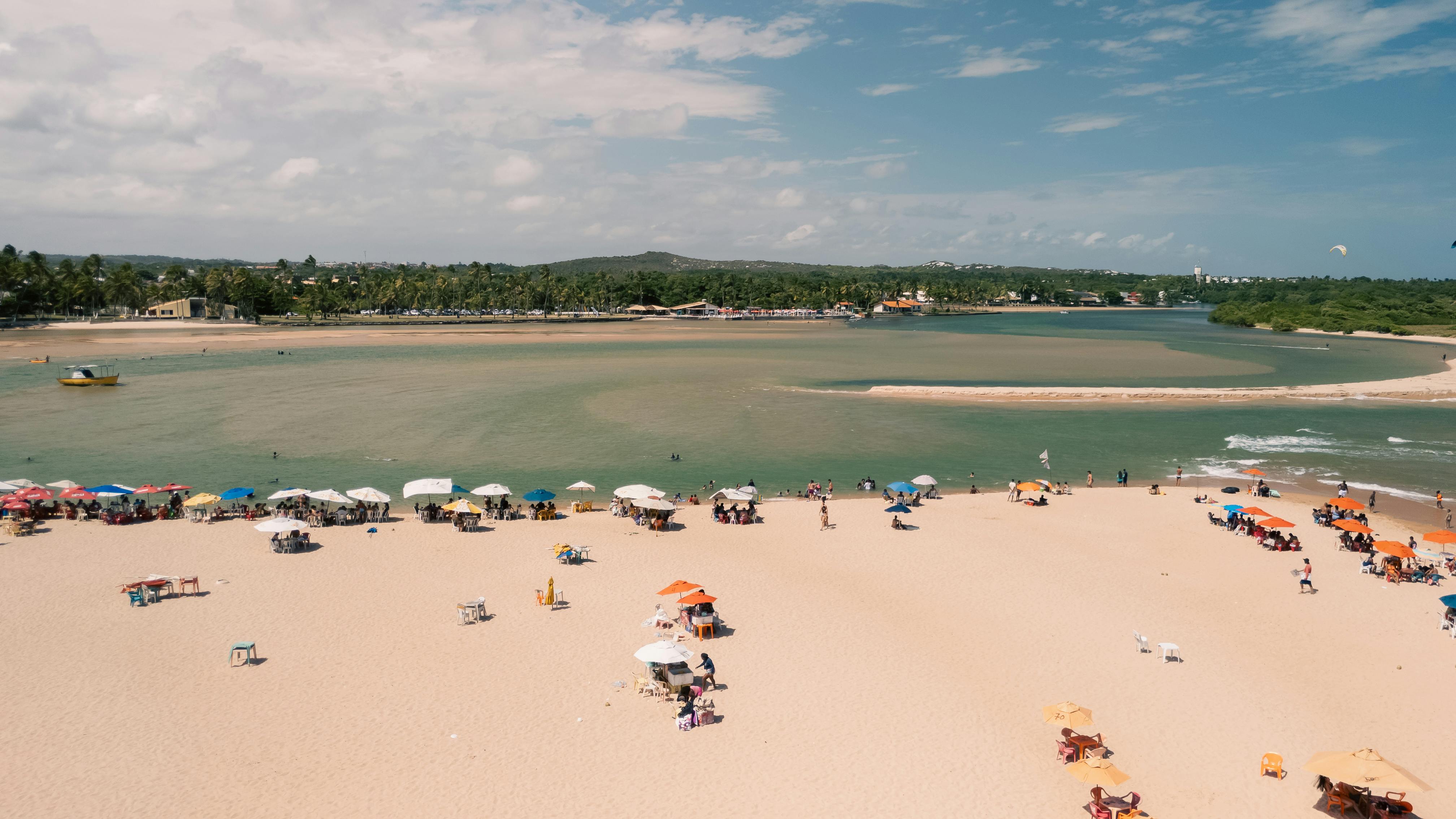 Aerial view of a vibrant beach in Lauro de Freitas, Bahia, Brazil with umbrellas and people.