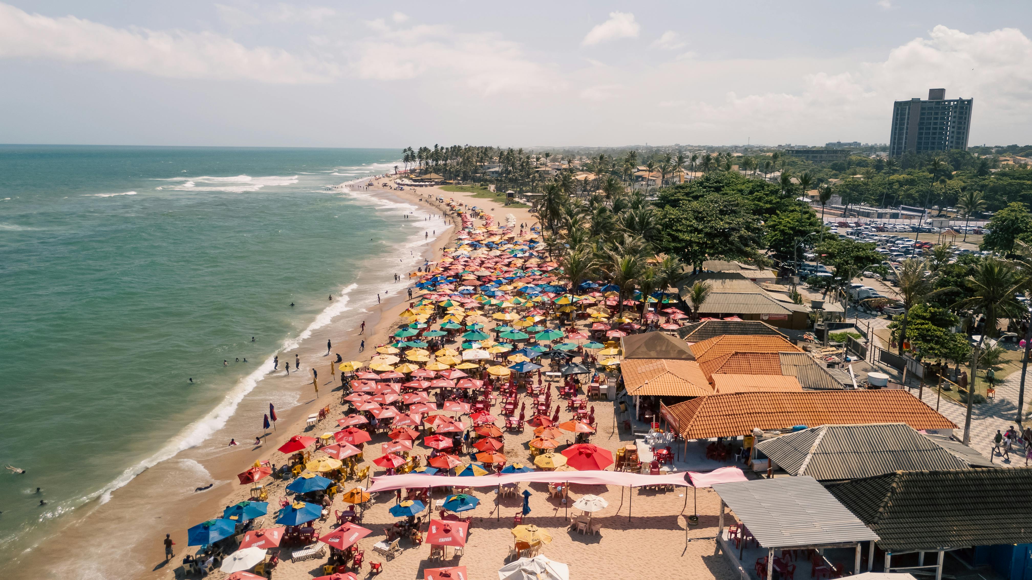 Vibrant beach scene with colorful umbrellas in Lauro de Freitas, Bahia, Brazil.