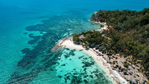 Free Stunning aerial shot of a pristine tropical beach with turquoise waters and lush greenery. Stock Photo