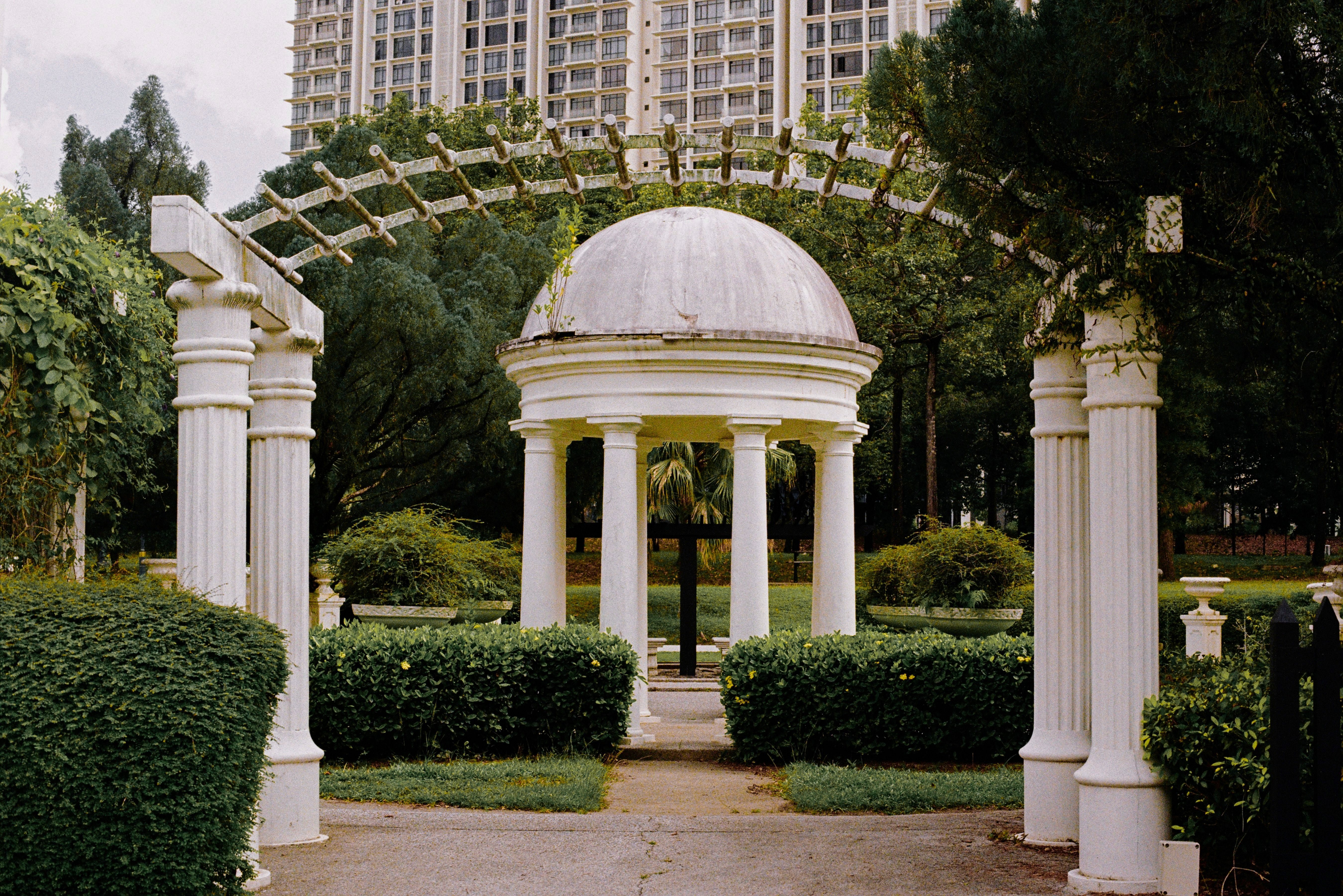 Beautiful white gazebo with pillars in a lush Malaysian garden. Perfect for serene moments.