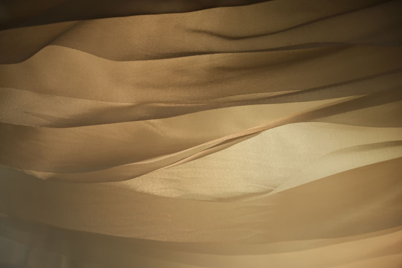Folds of golden fabric caught in raking light — photo by cute 嘟 on Pexels