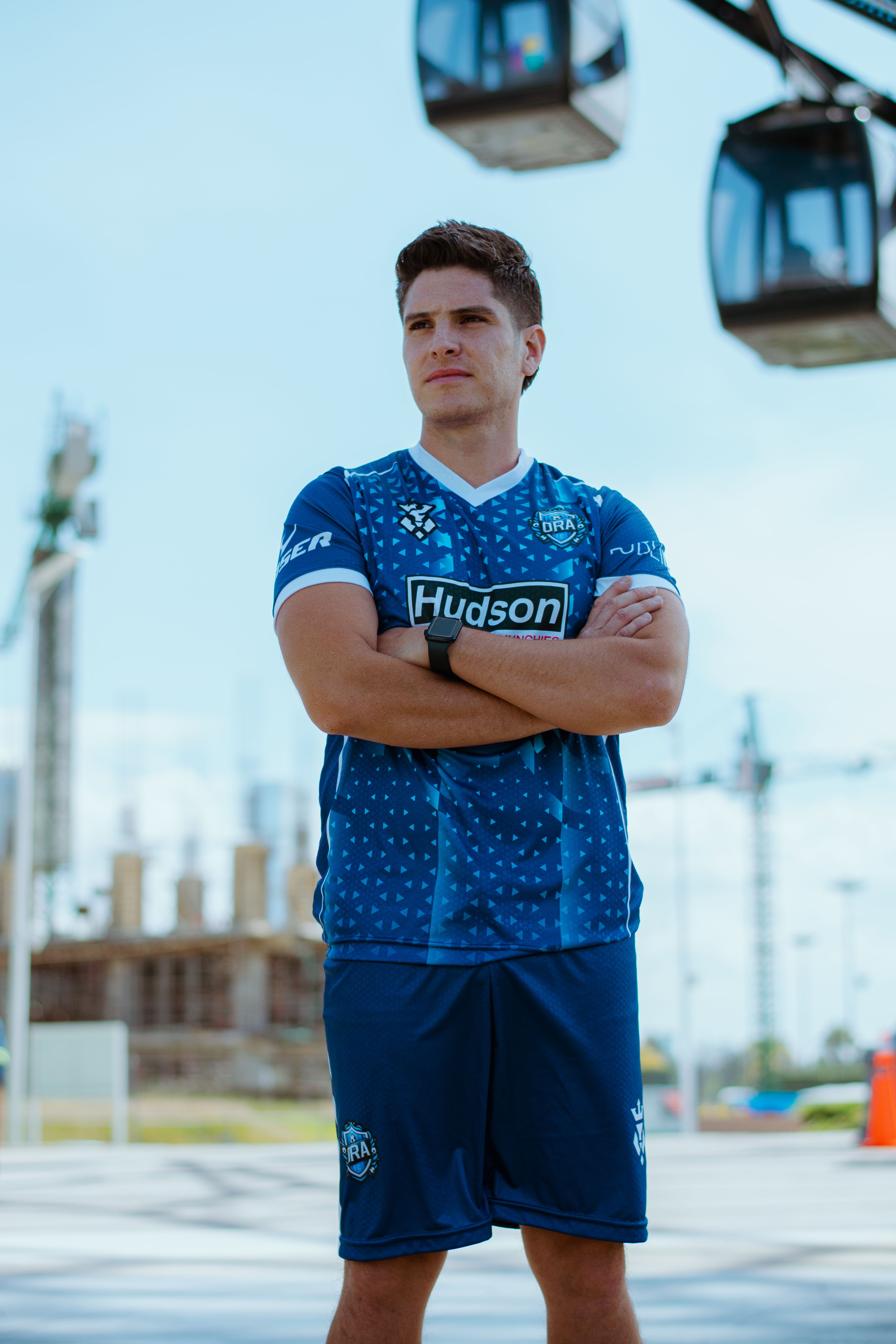 Confident man in sportswear posing outdoors near cable cars in Puebla.