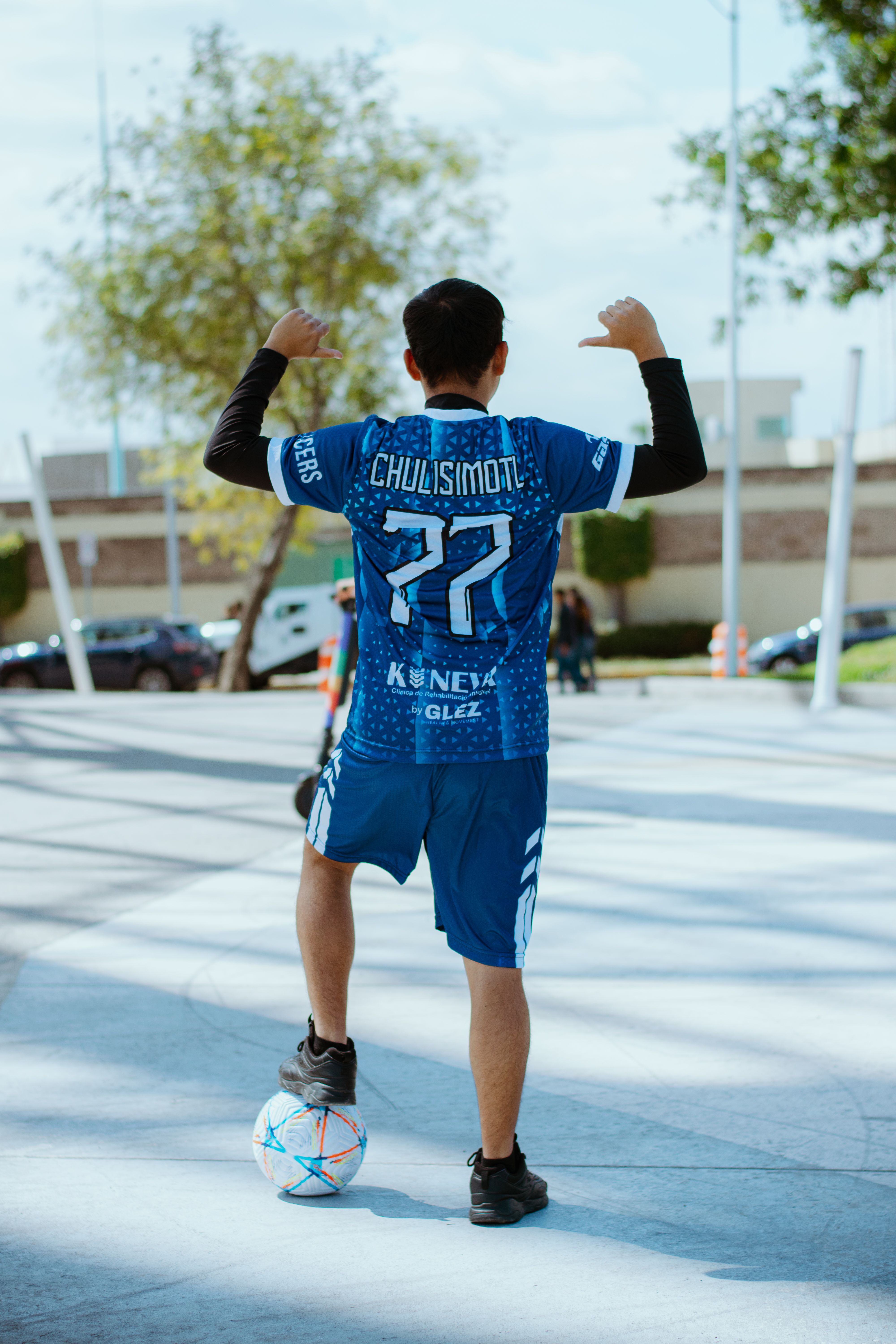 Teen soccer player poses confidently outdoors with a ball at his feet in Puebla, México.