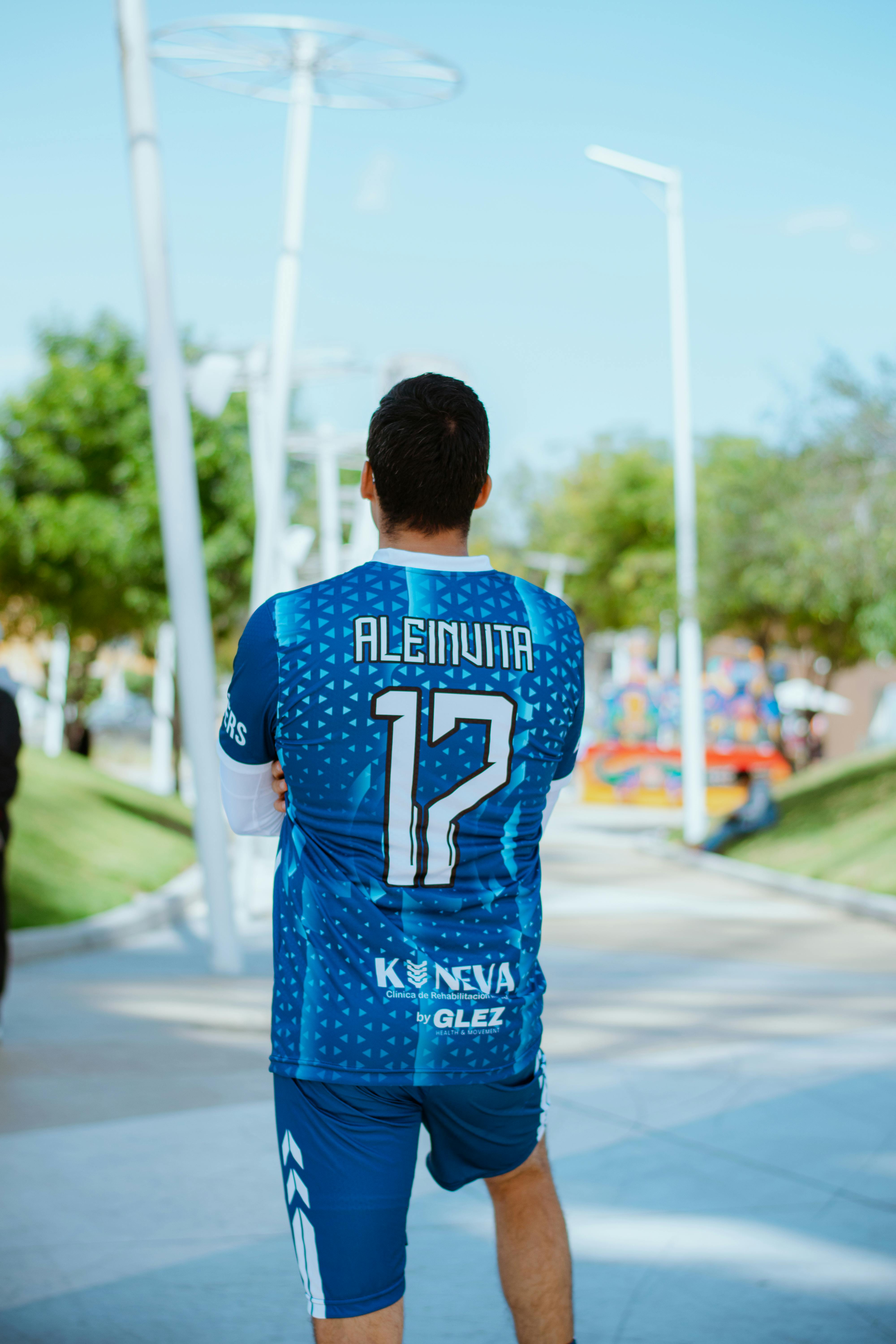 Man in sports jersey walking outdoors, showcasing athletic wear.